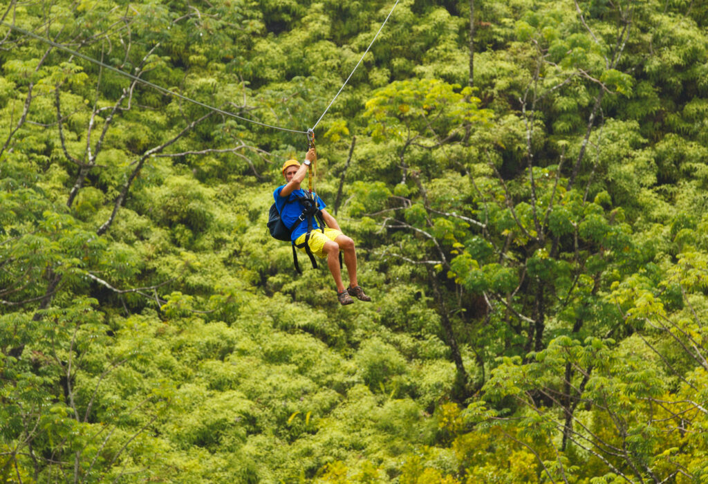 Man on Zipline over Lush Tropical Valley